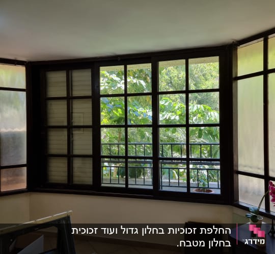 חלונות זכוכית גדולים עם מסגרות עץ כהות